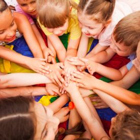 Gruppe Kinder mit übereinander gelegten Händen für Motivation im Sport
